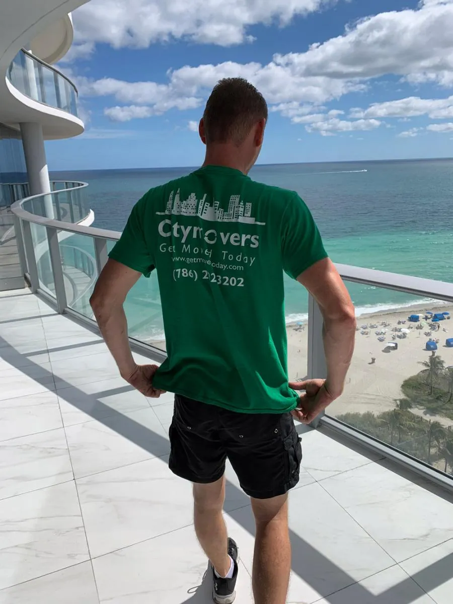 City Movers crew member in green company t-shirt on an oceanfront balcony