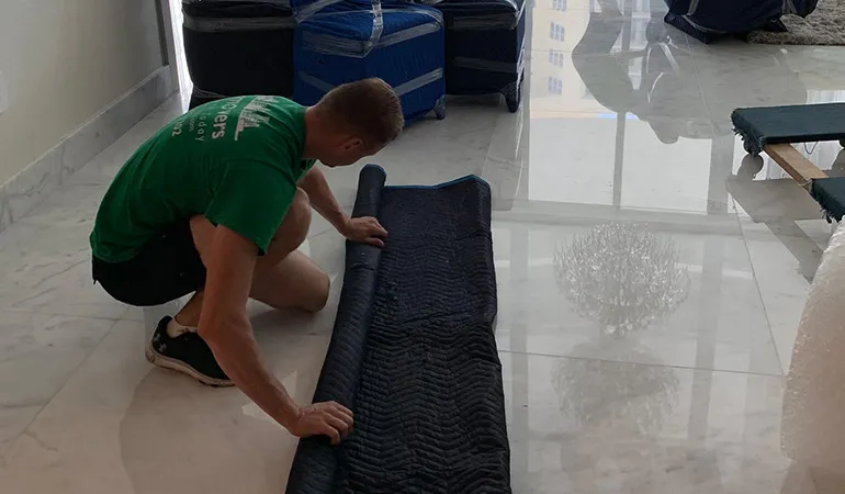 Mover rolling out protective padding on a marble floor