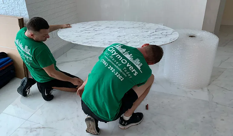 Two movers protecting a marble table top