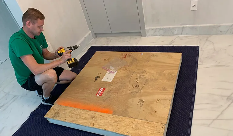 Mover crating a glass table top with a power drill