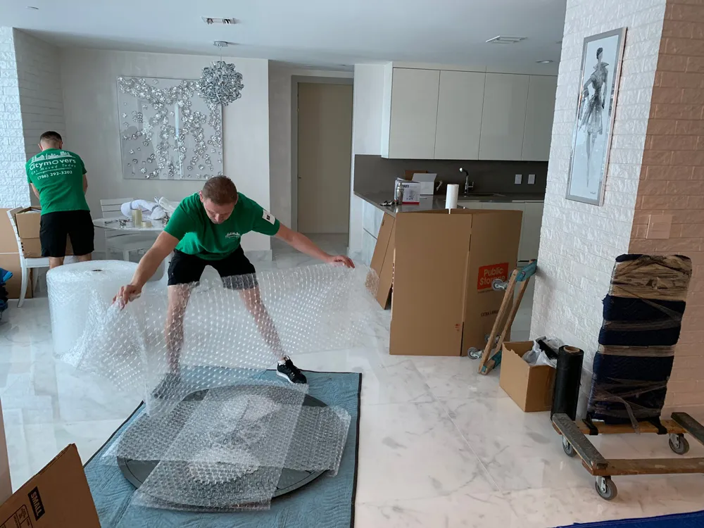 Movers wrapping a glass table in a luxury condo