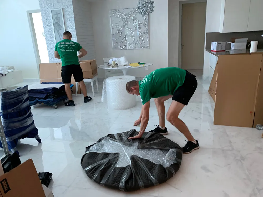 Mover wrapping a round table top in bubble wrap and padding