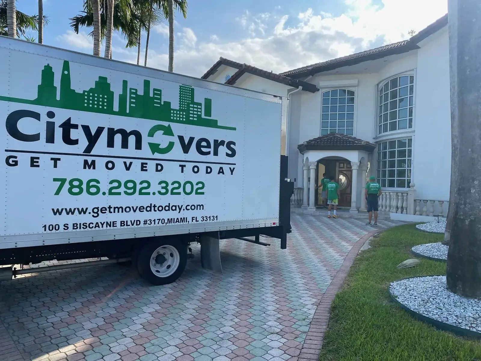 City Movers branded box truck parked in front of a white Miami mansion